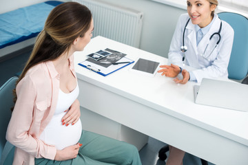 Obraz premium beautiful pregnant woman having consultation with gynecologist in clinic