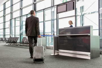 Rear view of mature businessman walking with his suitcase on his gate for boarding in airport