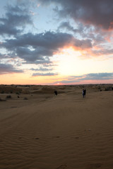 Fototapeta na wymiar People in the desert during amazing sunset