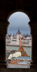 Fototapeta na wymiar Hungarian Parliament Building seen through a arcade of fishermans bastion on Buda Castle Hill, Budapest with