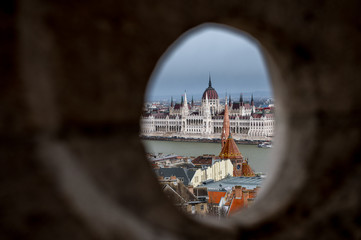 Obraz premium look through a hole in fishermans bastion on Buda Castle Hill, Budapest with Hungarian Parliament Building
