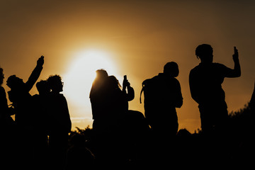 FLORENCE, ITALY - MARCH 05, 2019: Silhouettes of people taking pictures of the sunset with mobile phones and selfie stick on a sunset in Florence, Italy. Rear view.