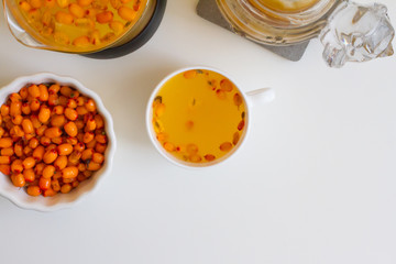 Vitamin useful sea buckthorn tea in a glass teapot with fresh sea buckthorn berries, orange, cinnamon sticks and honey. The concept of rest, relaxation. top view with a copy of the space