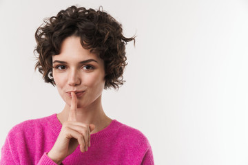 Image of pleased woman making silence gesture and looking at camera
