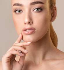 Fototapeta na wymiar Attractive Woman Touching Lips Posing On Beige Studio Background, Cropped