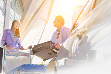 Portrait of mature man putting luggage on car trunk with lens flare © MDBPIXS