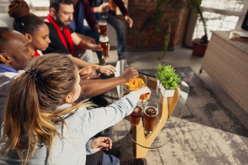 Excited group of people watching football, sport match at home. Multiethnic group of friend, fans cheering for favourite national basketball, tennis, soccer, hockey team. Concept of emotions, support.