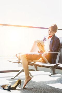 Young Beautiful Airport Staff Using Digital Tablet While Sitting On Chair During Break