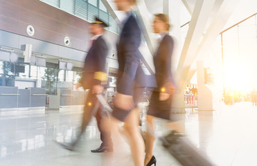 Mature pilot with young beautiful flight attendants walking in airport © MDBPIXS