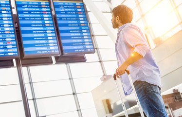 Low angle view of man looking at his flight on screen in airport