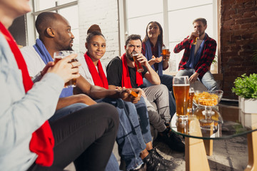 Excited group of people watching football, sport match at home. Multiethnic group of friend, fans cheering for favourite national basketball, tennis, soccer, hockey team. Concept of emotions, support.