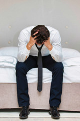 Fototapeta premium Stressed and overworked businessman sitting on the bed