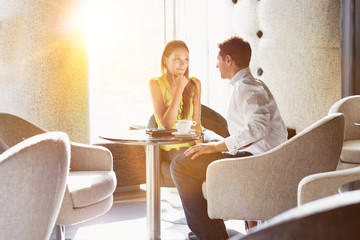 Businessman sitting while discussing plans with business partner in lobby