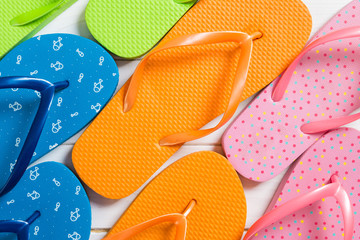 a lot of flip flop colored sandals, summer vacation on wooden background, copy space top view