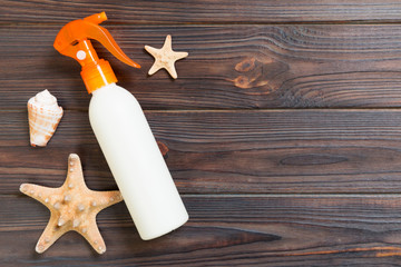 sun protection cream bottles with seashells on dark wooden table with copy space. Travel healthcare accessories top view