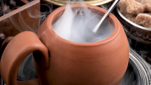A cup of hot coffee with smoke stirring with a spoon 