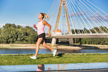 Portrait of young attractive woman running in park