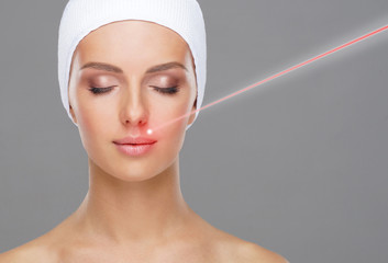 Doctor removing birthmarks with a laser ray. Beautiful face of a young woman. Mole removal, plastic surgery, skin lifting and aesthetic medicine.