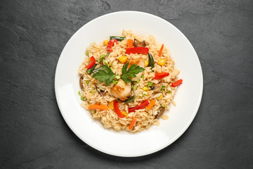 Delicious rice pilaf with chicken and vegetables on black table, top view