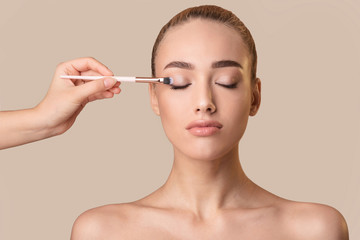 Hand Applying Eye-Shadows To Girl Using Cosmetic Brush, Studio Shot
