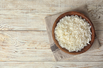 Bowl with tasty cooked rice on white wooden table, flat lay. Space for text