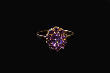 Fototapeta premium Beautiful golden ring with purple gemstone isolated on black background