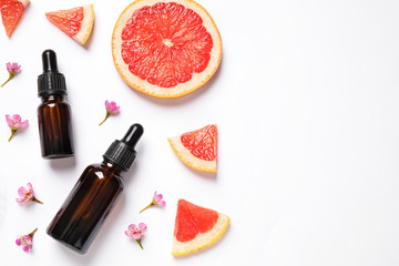 Flat lay composition with bottles of citrus essential oil on white background. Space for text