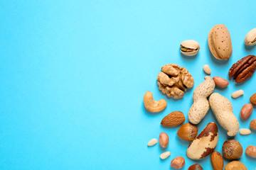 Fototapeta na wymiar Different delicious nuts on light blue background, flat lay. Space for text