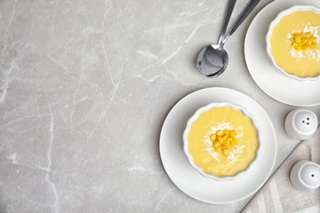 Delicious corn cream soup served on grey marble table, flat lay. Space for text