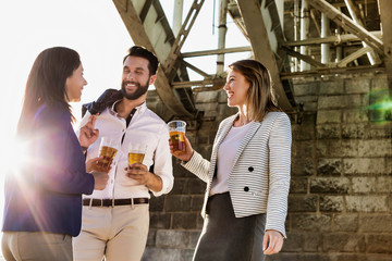 Business people celebrating success while drinking beer with lens flare in background