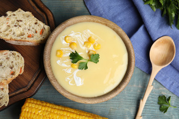 Delicious corn cream soup served on light blue wooden table, flat lay