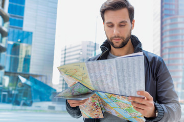 Portrait of young attractive man looking on the map in the city