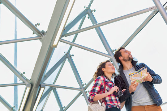 Portrait of young attractive couple looking on the map in the middle of the city