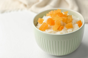 Delicious rice pudding with dried apricots on white table, closeup. Space for text
