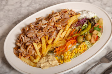 Turkish food dish. Chicken kebab meat, hummus fries and salad.