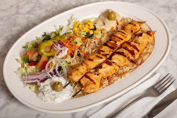 Plate of Turkish food Sish Tavuk, hummus fries and salad.