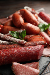 Different tasty sausages on wooden table, closeup