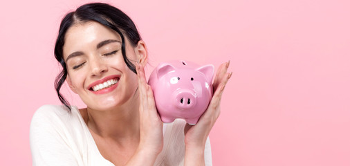 Young woman with a piggy bank on a pink background