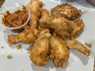 Fried chickens on a plate with spicy sauce.