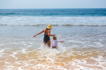 A woman with child by the hand goes along the sea shore