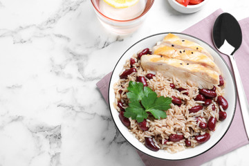 Delicious rice with beans and meat served on white marble table, flat lay. Space for text