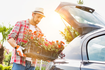 Portrait of mature gardener putting flowers on car trunk for delivery © MDBPIXS