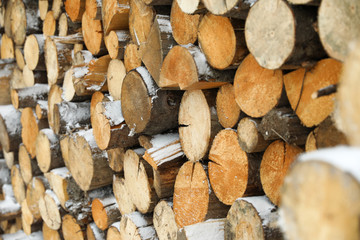 Stacked firewood with snow as background, closeup. Heating house in winter