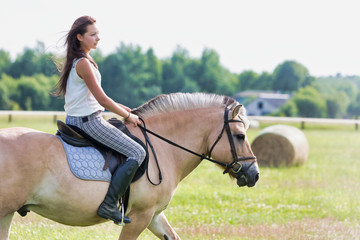 Obraz premium Portrait of young attractive woman riding horse in ranch