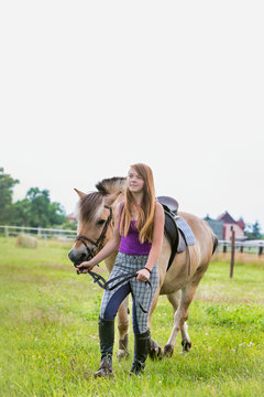 Portrait of young beautiful woman standing with horse in ranch