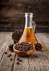 Pine nuts, oil and cedar cones on rustic wooden background.  Organic and healthy superfood.
