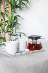 Teapot and cups setup on a tray with bamboo plant in the background