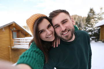 Young couple taking selfie on snowy day. Winter vacation