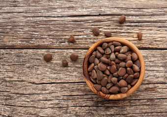 Pine nuts in wooden bowl on rustic wooden background.  Organic and healthy superfood. Top view.