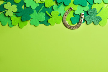 Flat lay composition with clover leaves and horseshoe on green background, space for text. St....